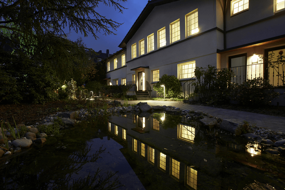 Gästehaus bei Nacht mit Teichbeleuchtung